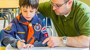 Cub Scout learning with his father